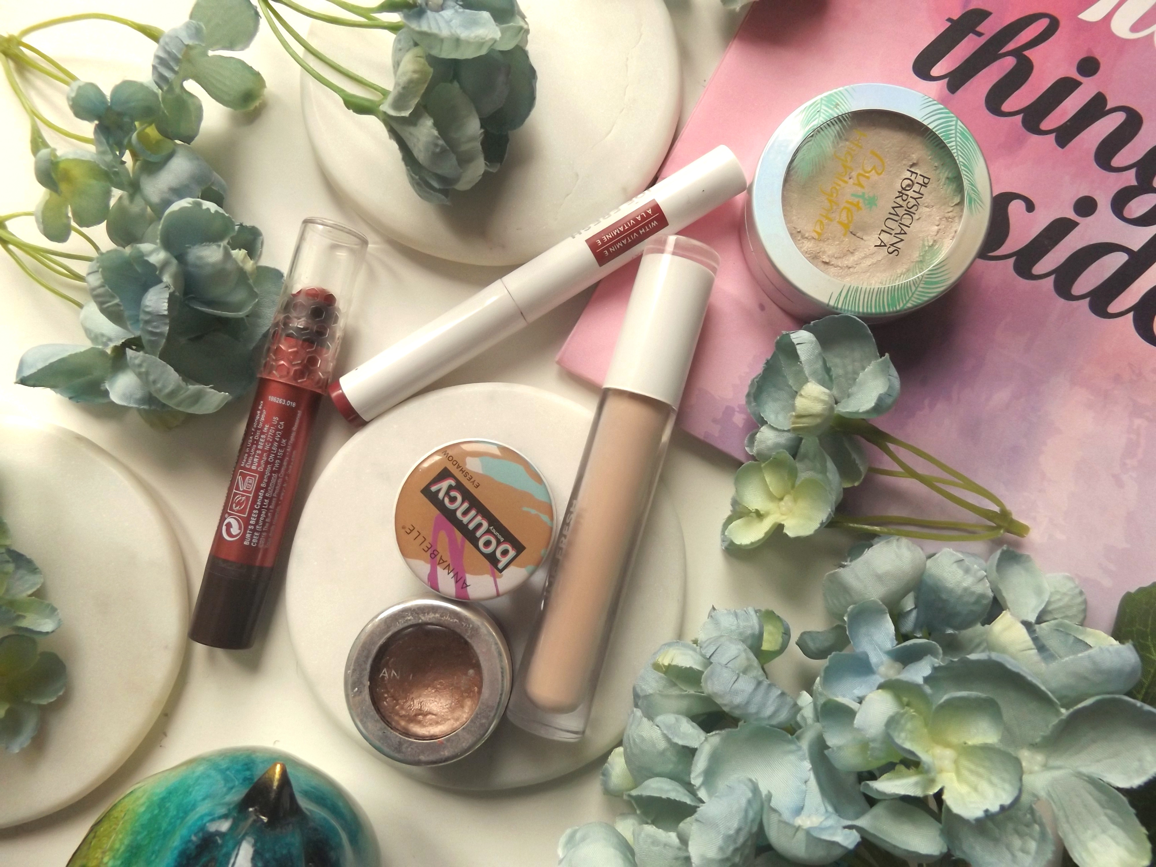Flatlay - clockwise from the left: Burt's Bees Tahitian sunset, Joe Fresh powder lip product, Joe Fresh concealer, Physicians formula butter highlighter, Annabelle Chrome eyeshadow in rose gold, Annabelle bouncy eyeshadow in booty shake.