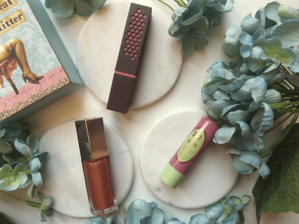 Clockwise from the bottom: Fenty Gloss balm, Burt's Bees Peony Dew, pixi natural rose lip balm